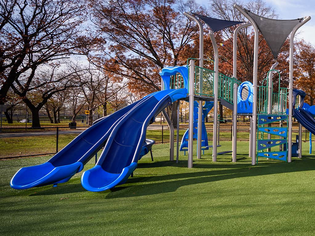 Blue color accent playground with autumn colored trees in the background